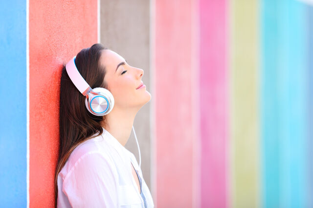 fille calme qui écoute de la musique devant mur coloré